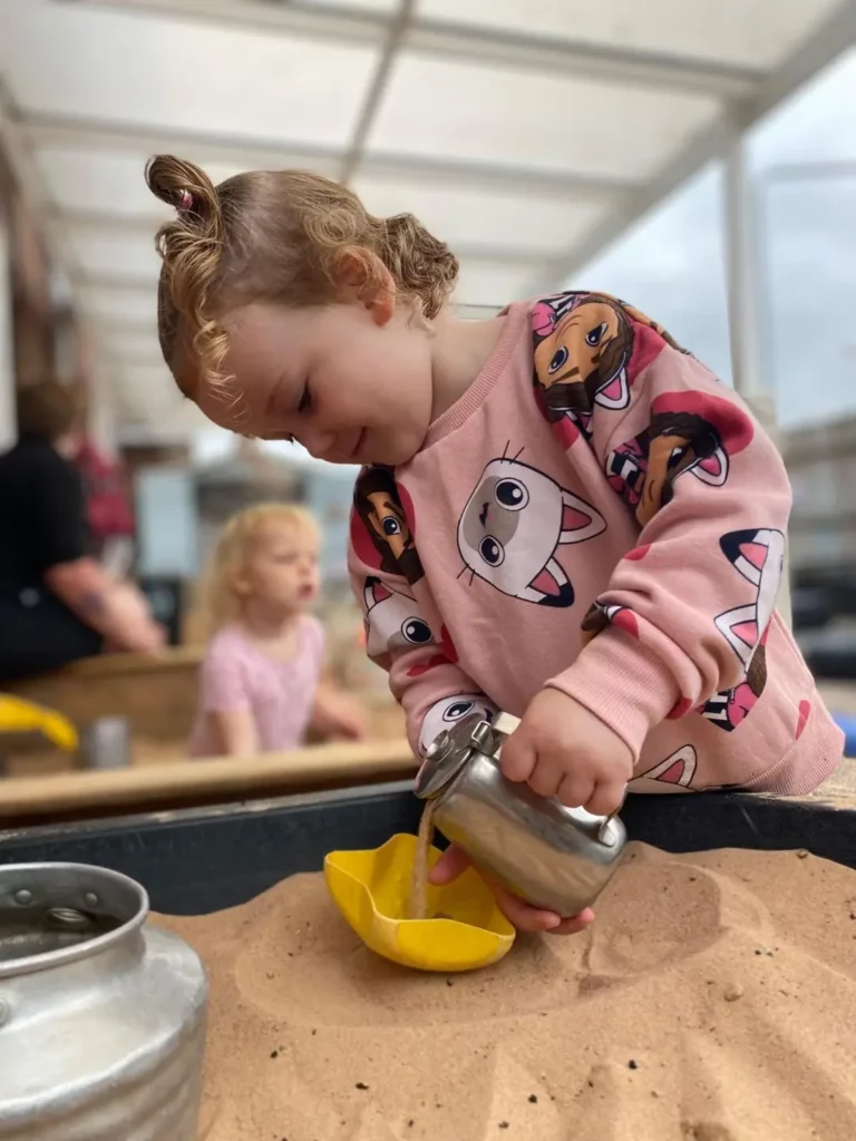 A child pouring water in the sandpit