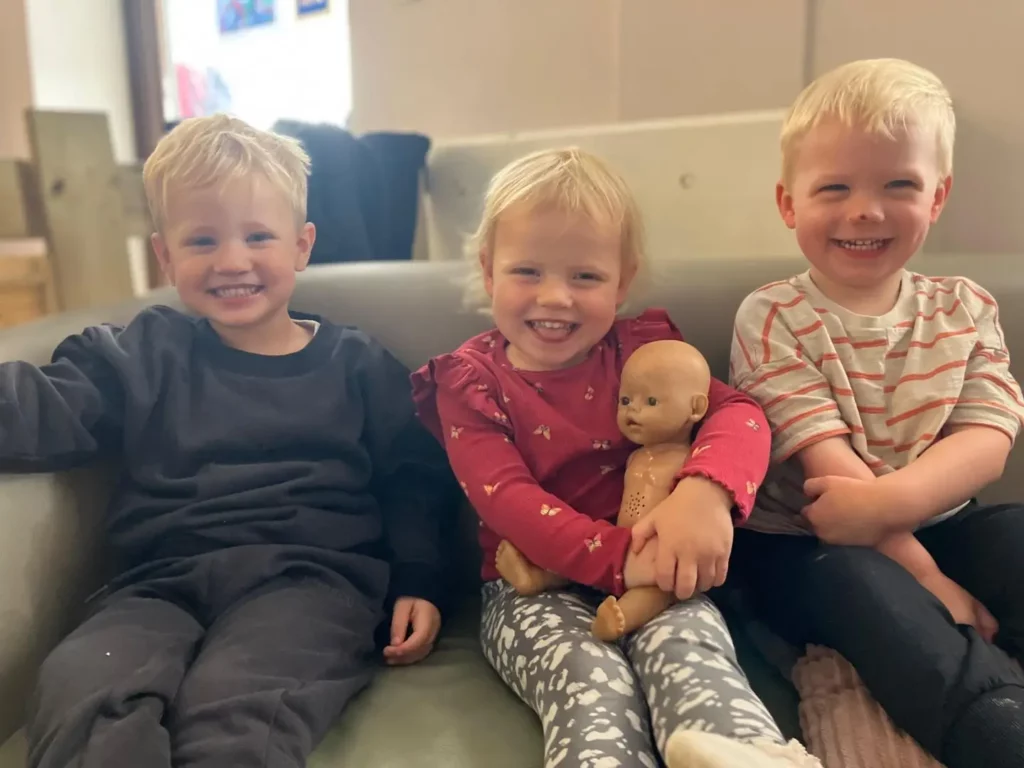 Children sat together on a sofa smiling